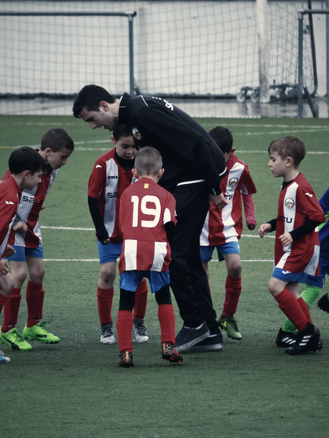 Entrenador dando indicaciones a un grupo de jugadores infantiles en la cancha