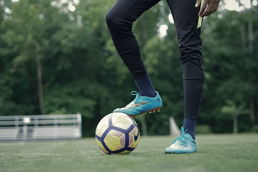 Jugador con el balón dominado entre conos de entrenamiento