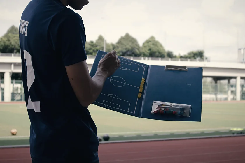 Entrenador revisando una pizarra táctica