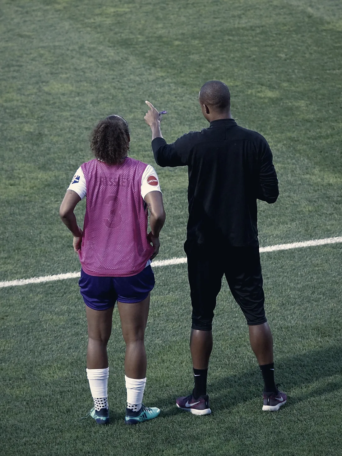 Entrenador orientando a una jugadora al costado de la cancha